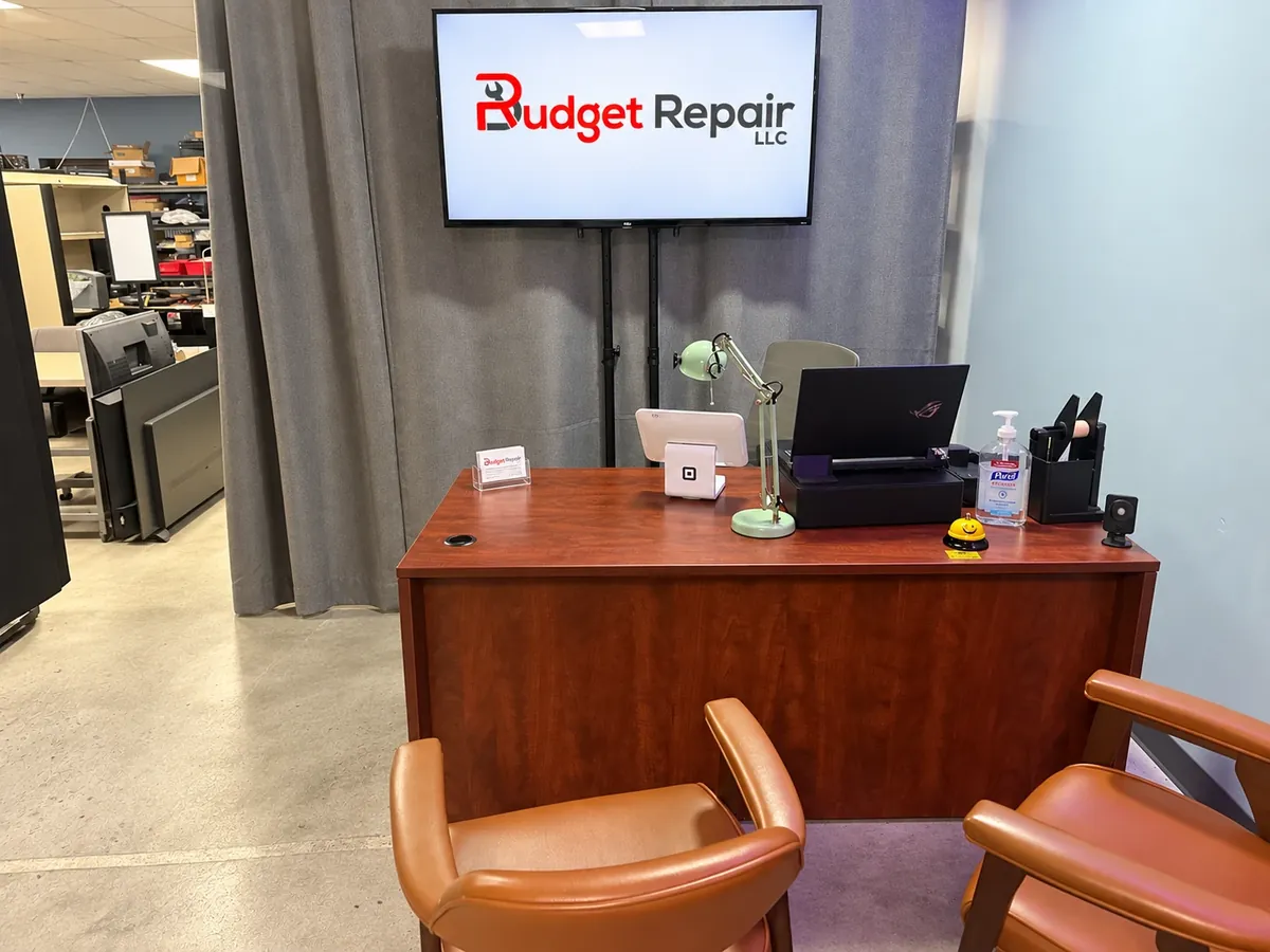 Budget Repair front desk with the Budget Repair logo on a wall-mounted TV and two customer chairs