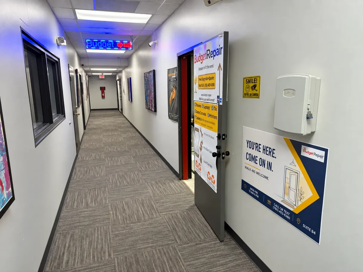 Downstairs hallway leading to Budget Repair Suite B4, with a lit Budget Repair sign and door posters
